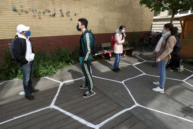 Students wearing protective face masks talk while practicing social distancing in the courtyard of a flemish secondary school during its reopening in Brussels, Belgium, May 15, 2020. REUTERS/Yves Herman